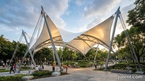 Durable tensile membrane shade structure in a public park with UV protection and wind load compliance for longevity