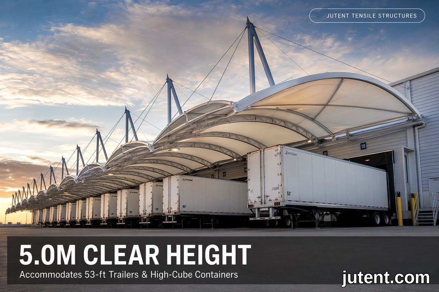 Wide-angle photo of a white PTFE tensile membrane loading dock canopy with 5.0m clearance, sheltering multiple 53-foot trailers at a modern warehouse
