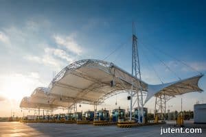 Toll plaza tensile membrane canopy with safety height clearances and wind load compliance for highway station