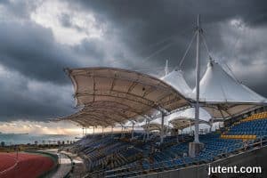 A large tensile membrane grandstand canopy designed for typhoon resistance in coastal Southeast Asia, featuring robust steel supports and corrosion protection.