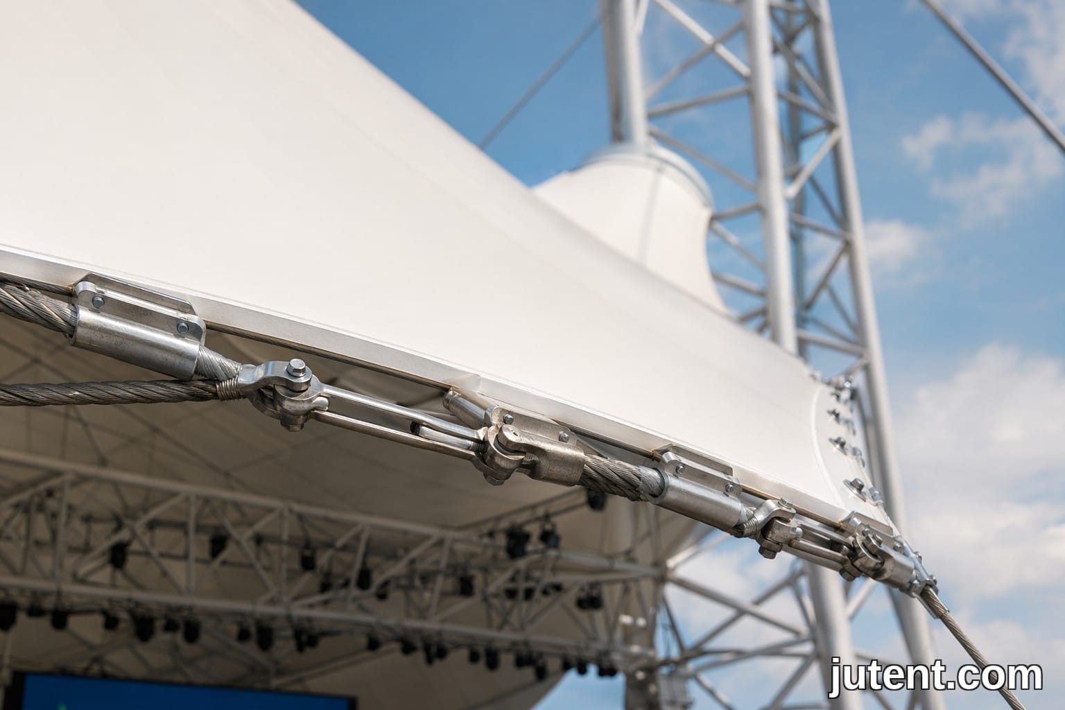 Close-up of a steel edge cable and clamp connection on a taut white PTFE tensile membrane stage canopy