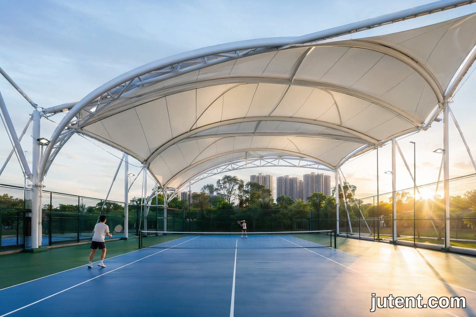 Aerial view of a white PVDF tensile membrane canopy covering three tennis courts without intermediate columns, providing glare-free shade in Manila