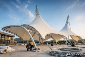 Modern hotel entrance with white tensile membrane canopy structure under blue sky, showcasing commercial tensile canopy cost factors for project budgets