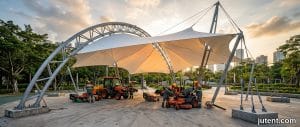 Heat-resistant tensile membrane park shade protecting playground equipment from burns under intense Middle East sun