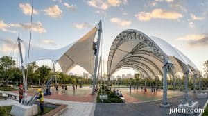 Aerial view comparing saddle and barrel vault tensile membrane canopies over sports courts, highlighting structural form differences
