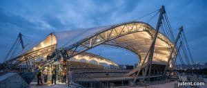 Vue aérienne d'un grand stade avec un auvent de tribune à membrane tendue blanche, illustrant les facteurs de coût pour les structures en porte-à-faux et haubanées