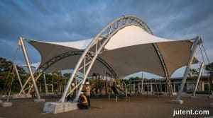 Engineer inspecting high-tension membrane playground shade structure designed for 200kmh typhoon winds in Southeast Asia