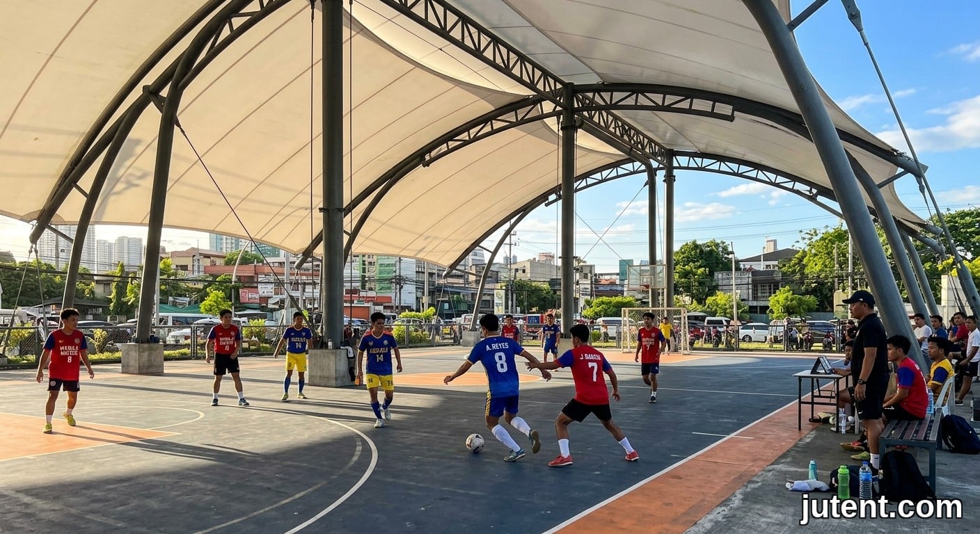 Foto spontan atlet Filipina bermain futsal di bawah struktur teduhan membran tegangan putih yang besar pada hari yang cerah, dengan cahaya keemasan dan suasana santai.