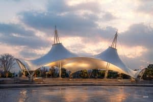 White tensile membrane park pavilion structure designed to combat uplift forces from coastal winds in a tropical island setting