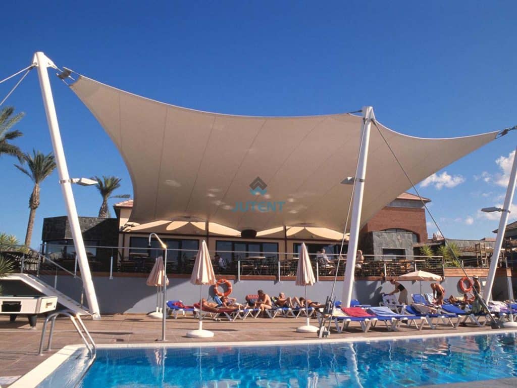 Tensile shade canopy covering swimming pool leisure seating area