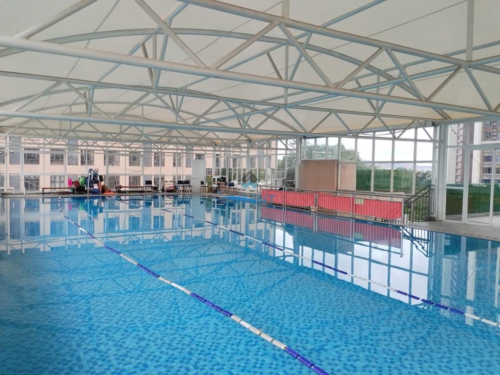 Swimming pool tensile membrane shade canopy covering outdoor pool area