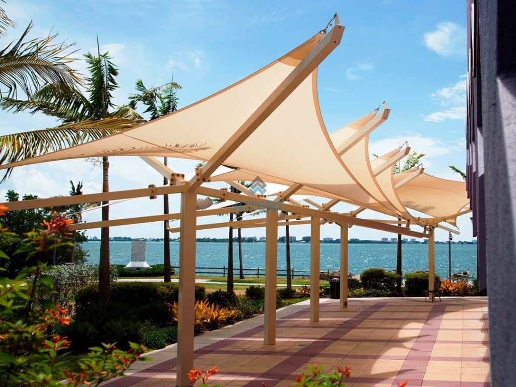 Tensile membrane walkway canopy installed between commercial buildings providing covered pedestrian corridor