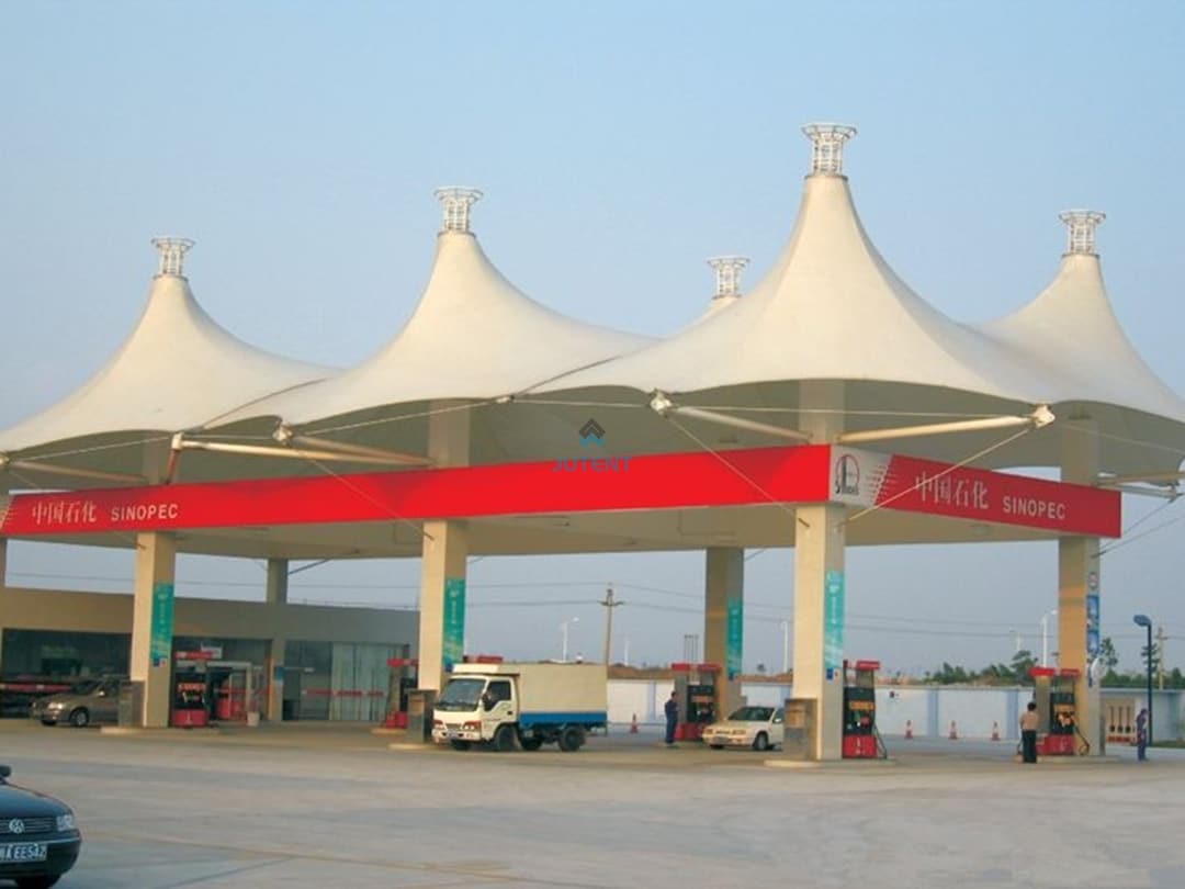 Gas station tensile canopy g10 Large span tensile membrane canopy providing multi-bay coverage for fuel pumps at commercial gas station.