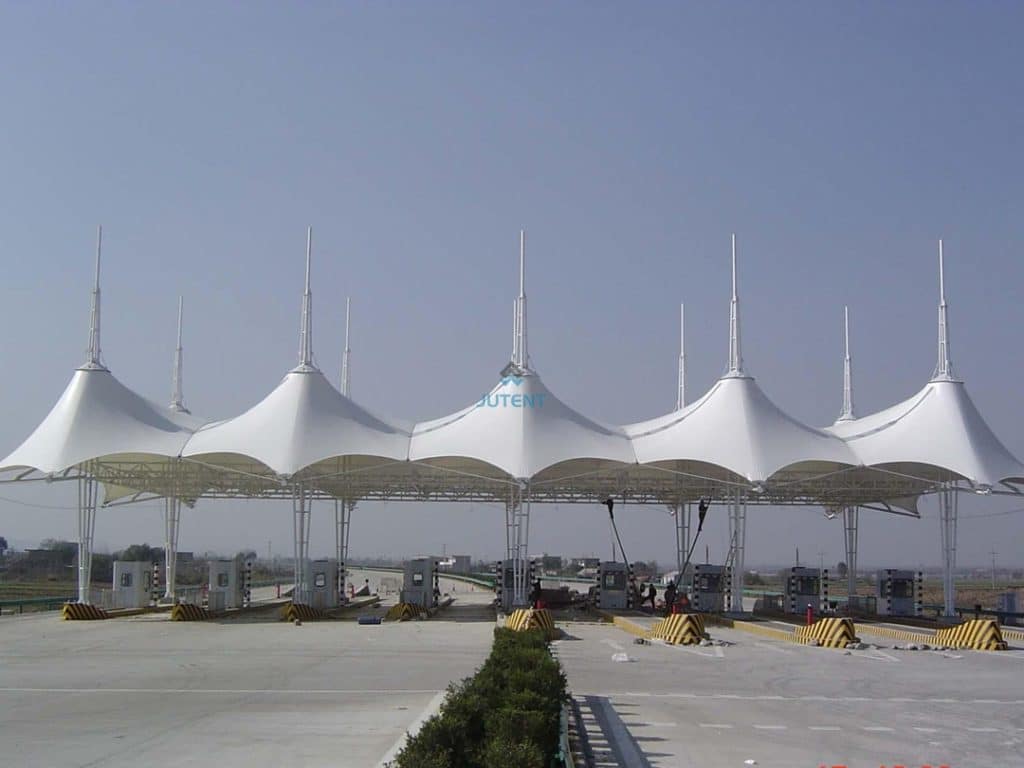 Large span tensile membrane canopy covering multiple lanes at a highway toll plaza.