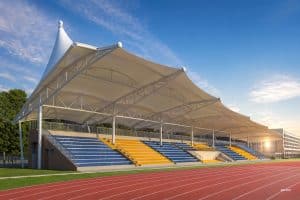 Modern tensile membrane shade structure covering aluminum school bleachers with spectators seated underneath